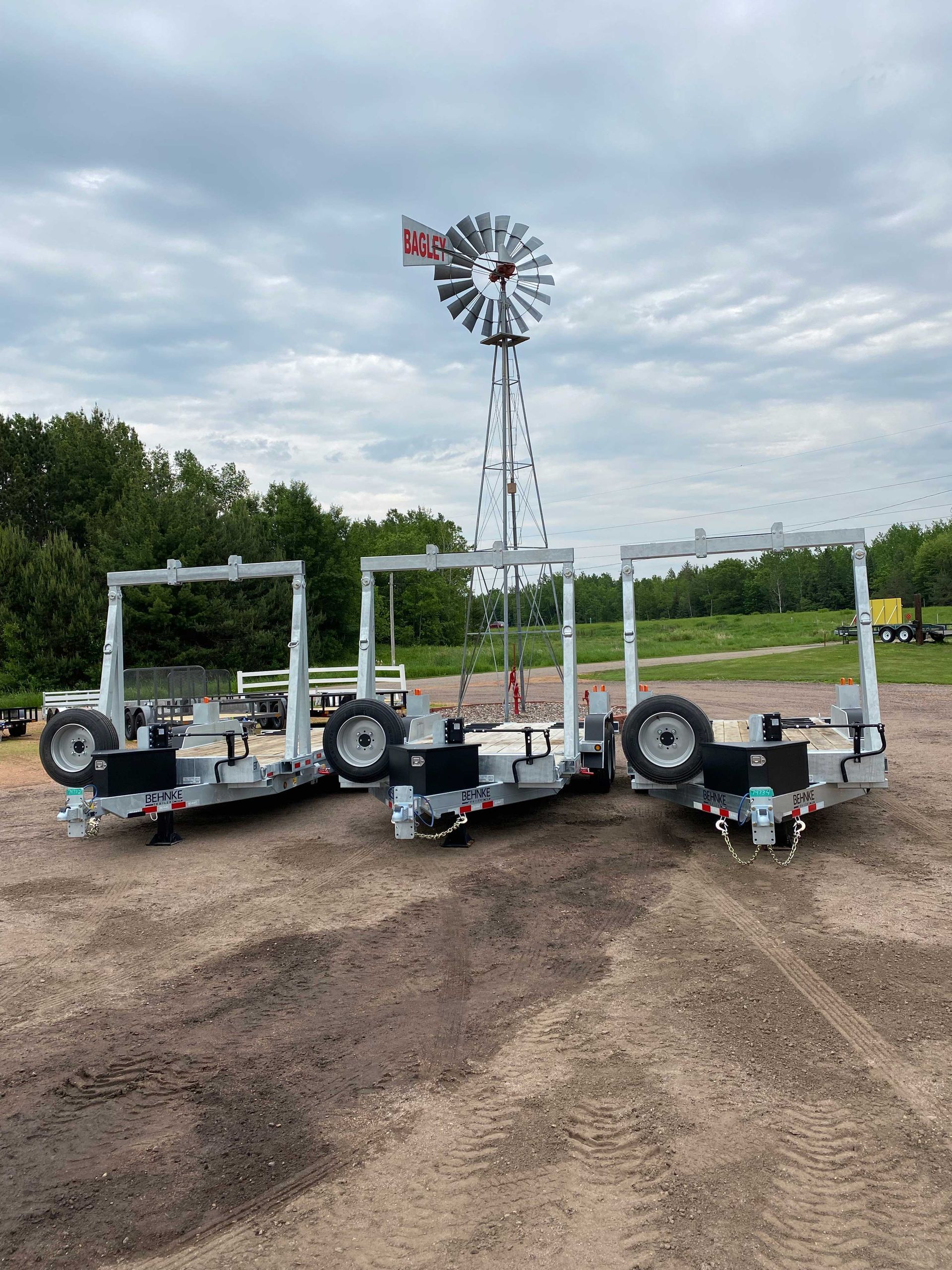Three silver trailers with black wheel components, windmill in background.