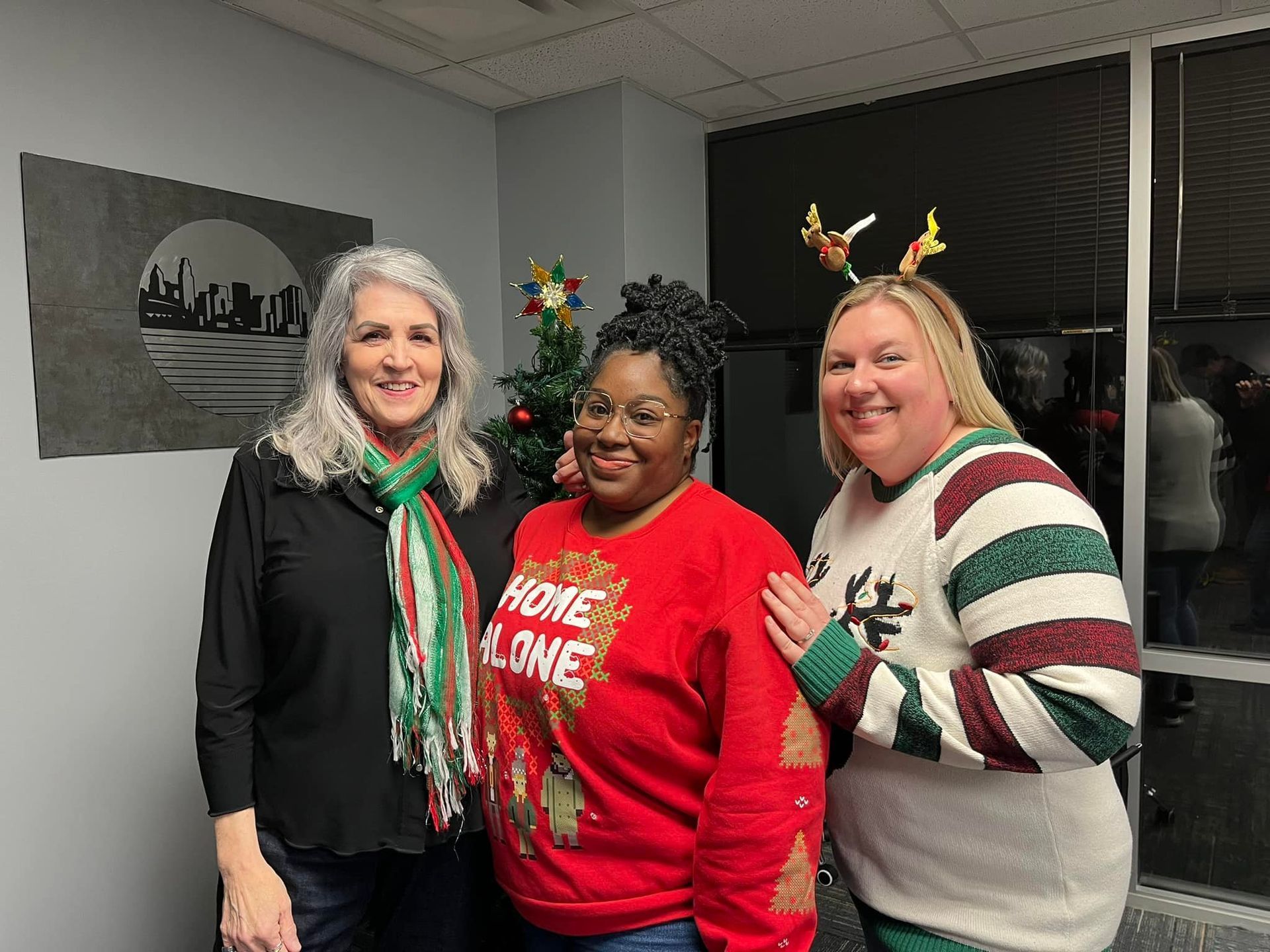 Three women are posing for a picture in front of a christmas tree.