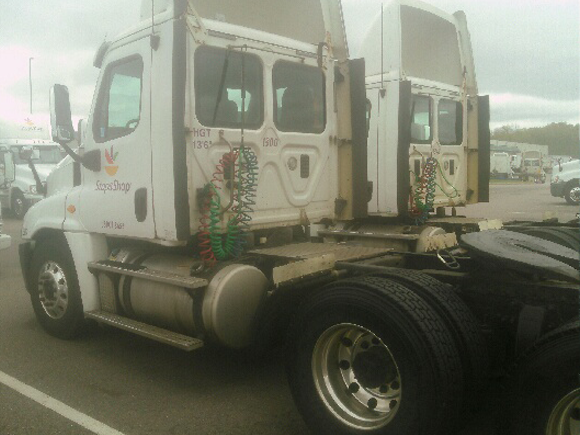 A white semi truck with a trailer is parked in a parking lot.