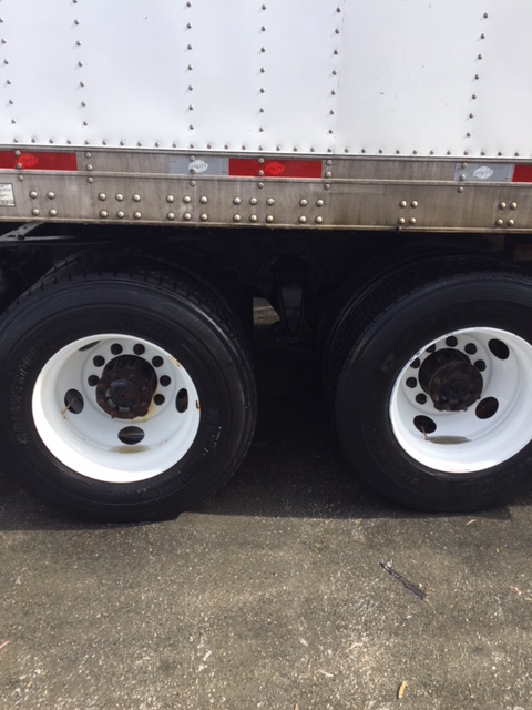 A white semi truck with black tires and white wheels