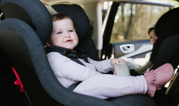 A baby is sitting in a car seat and smiling.