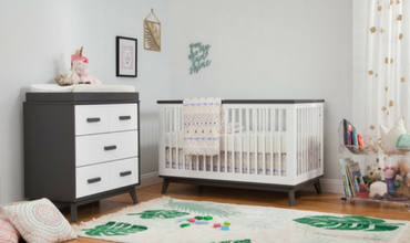 A nursery with a crib, dresser, and rug.