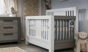 A baby 's room with a crib, dresser, and teddy bear.