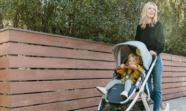 A woman is pushing a stroller with a baby in it.