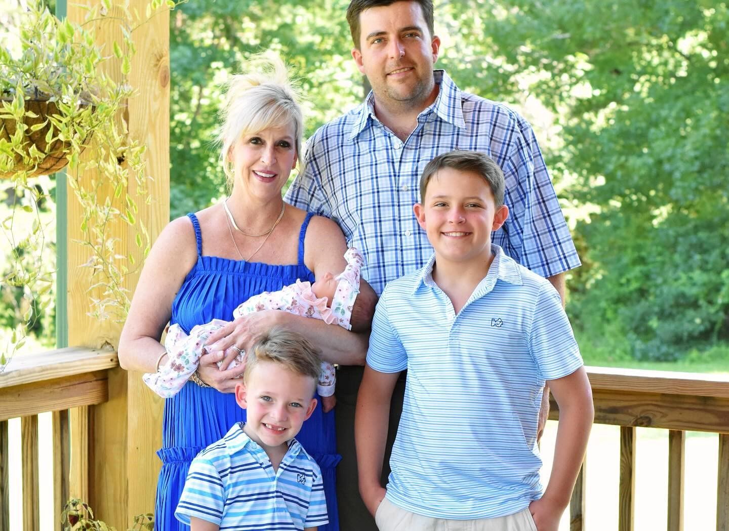A family is posing for a picture on a porch.