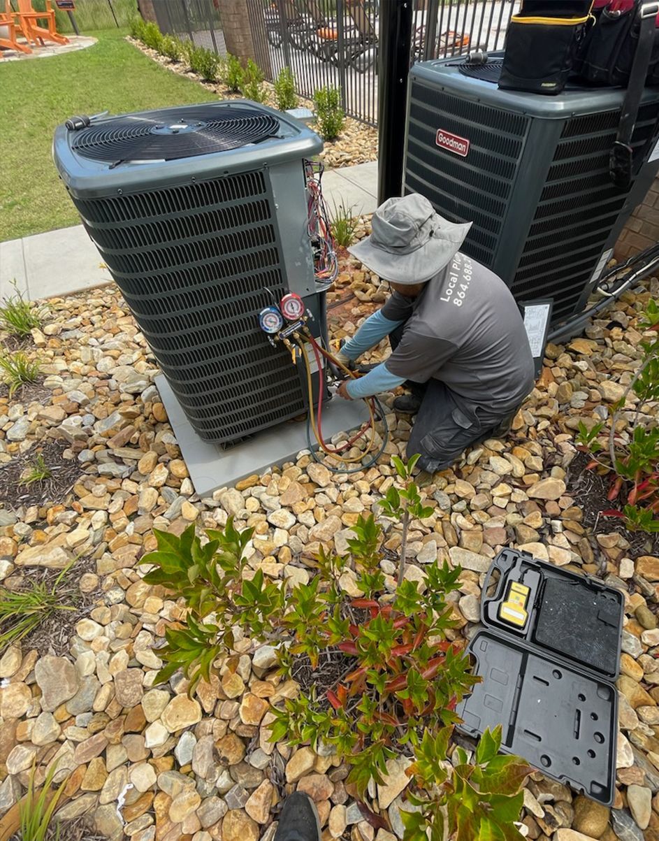A man is working on an air conditioner in a yard.
