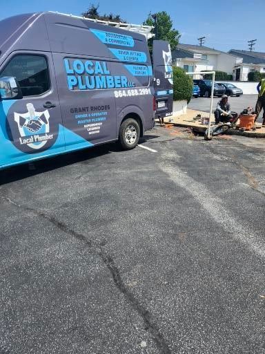A local plumber van is parked in a parking lot.
