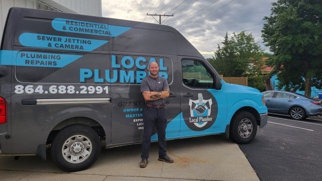 A man is standing in front of a local plumber van.