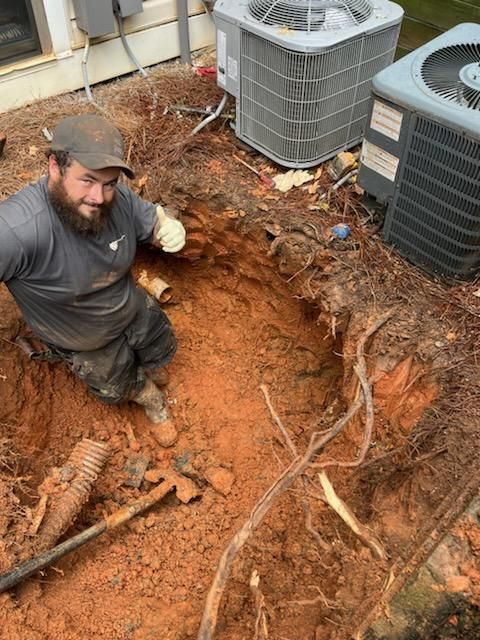 A man is crawling out of a hole in the ground.