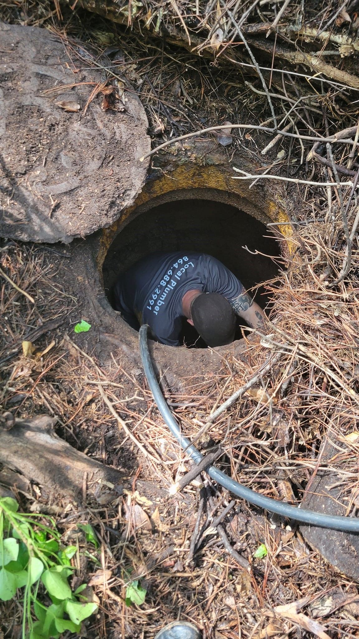 A man is crawling out of a hole in the ground.