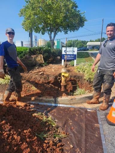 Two men are standing next to a fire hydrant on the side of the road.