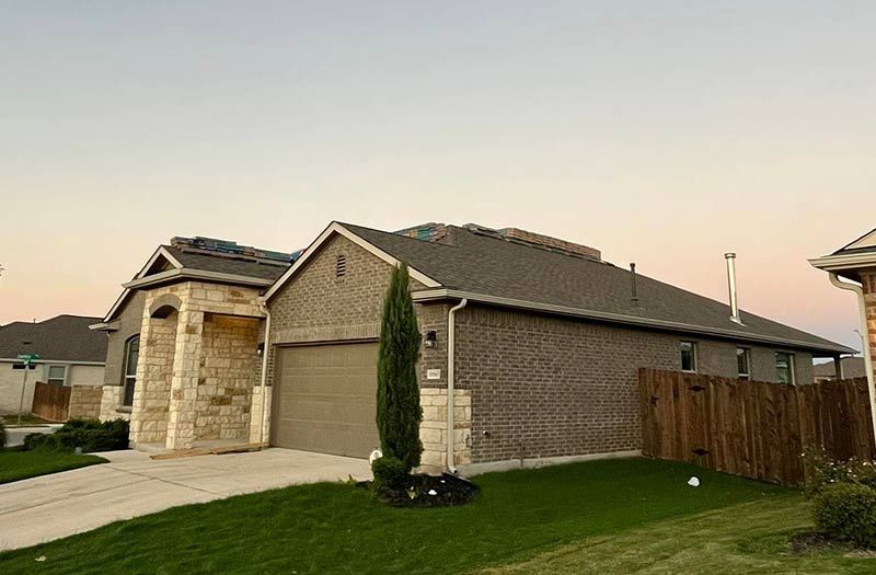 A brick house with a roof that has been damaged by a storm.