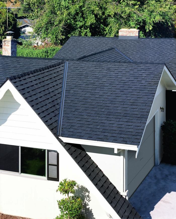 A white house with a black roof and a garage