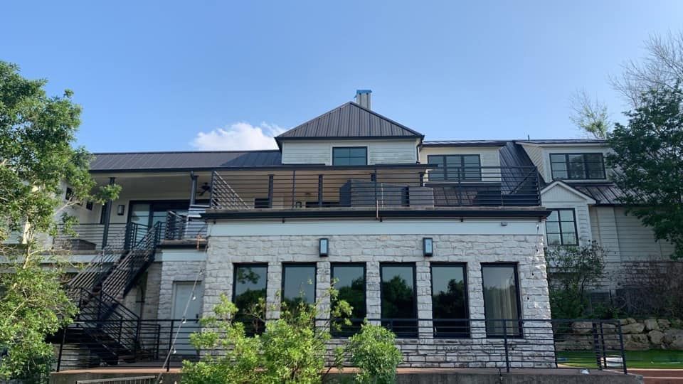 The back of a large house with a staircase leading up to the second floor.