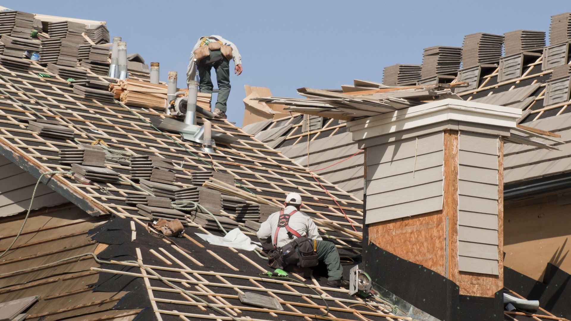 Two men are working on the roof of a house.