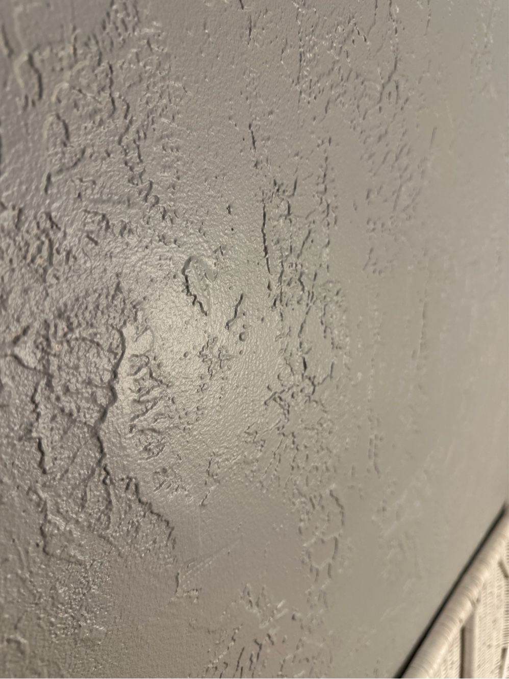 Textured gray painted wall with light reflections, corner of white trim visible.