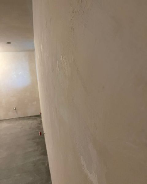 White drywall wall with patches and an unfinished interior room.