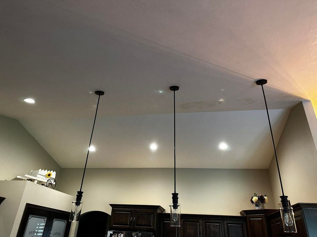 Kitchen ceiling with three pendant lights and recessed lighting.