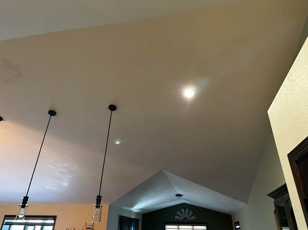 Angled beige ceiling with hanging lights, a visible recessed light, and a glimpse of a window.
