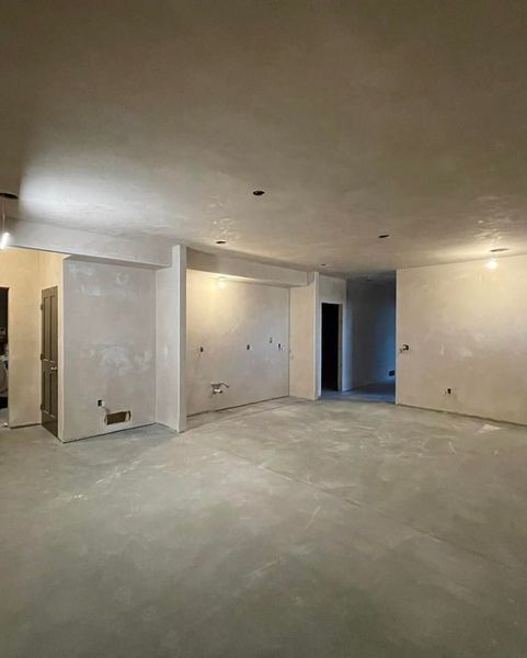 Empty, unfinished interior space with walls and floor covered in gray plaster.