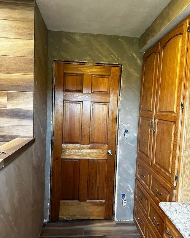 Wooden door in a kitchen with brown cabinets and light-colored walls.