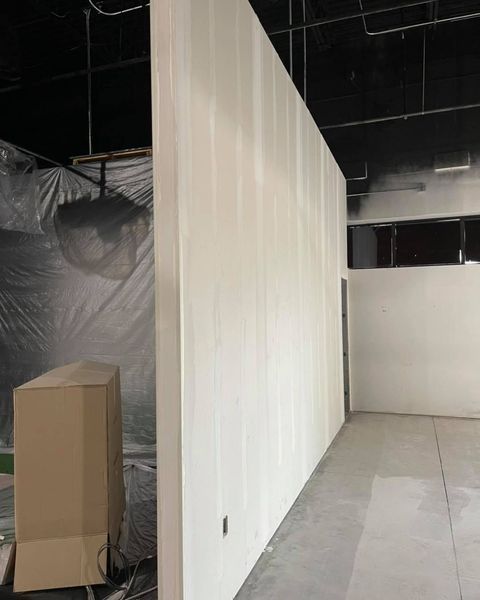 White painted wall in a construction space, cardboard box, and a doorway.
