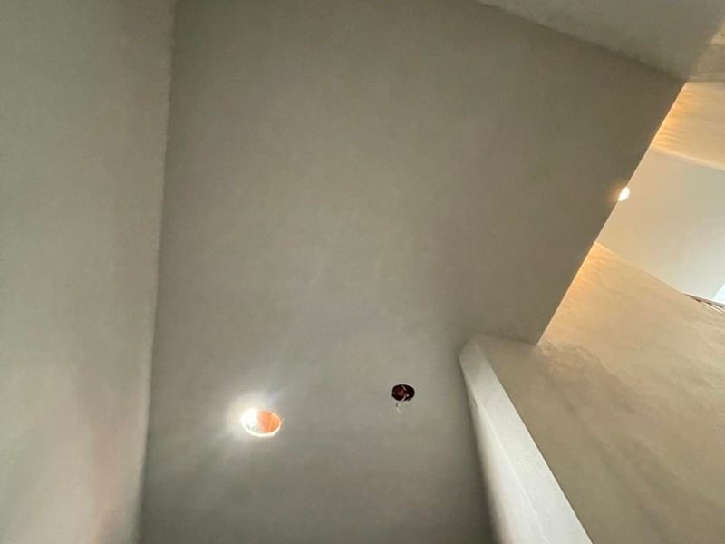 Interior view of a room with unfinished gray walls and ceiling, showing electrical fixtures.