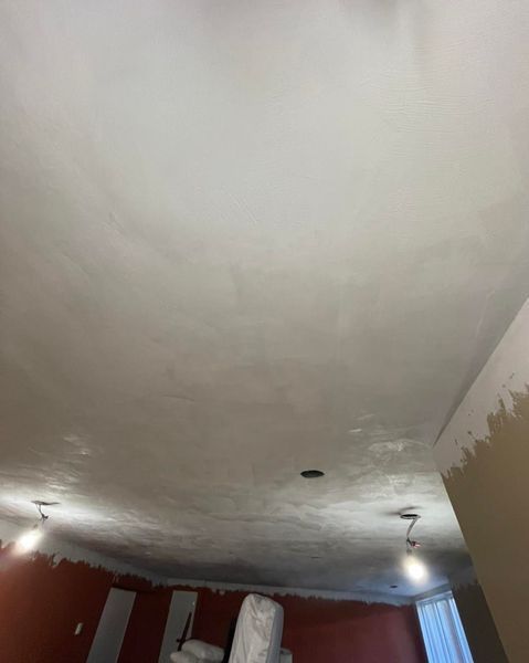 Newly plastered ceiling in a room with light fixtures and unfinished walls.