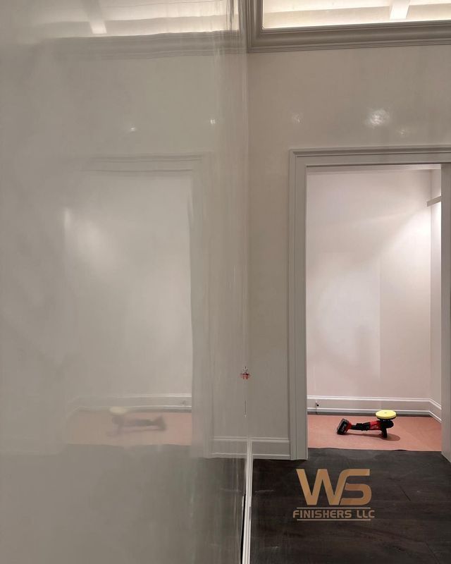 Hallway with white walls, a door frame, and a dark floor.