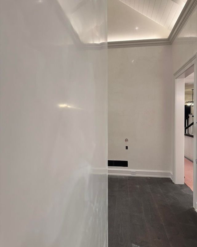 White-walled hallway with dark wood floor, leading to a door; ceiling has recessed lighting.
