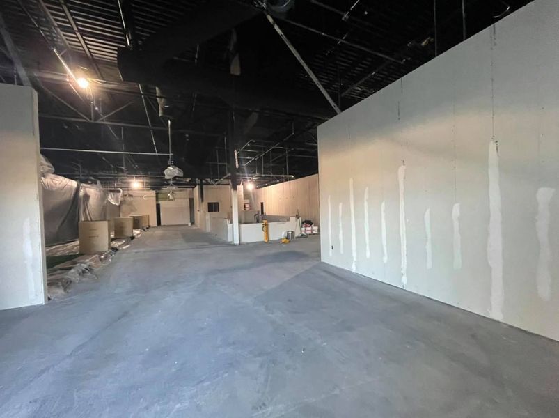 An interior construction site with drywall and a black ceiling.