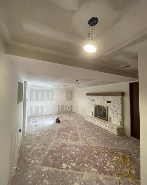 Interior renovation of a room with drywall, a fireplace, and exposed wiring.