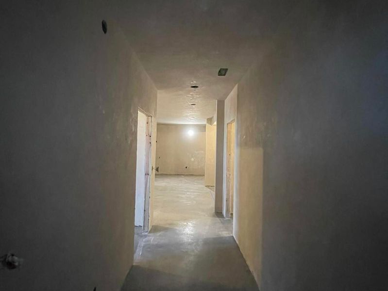 Empty hallway with gray walls and doorways; construction in progress.