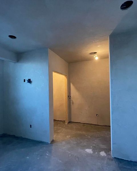 Interior room under construction with doorways, unfinished walls, and concrete floor.