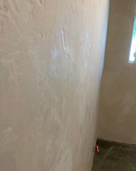 Textured, light-colored interior wall with slight imperfections. Corner of the room visible.