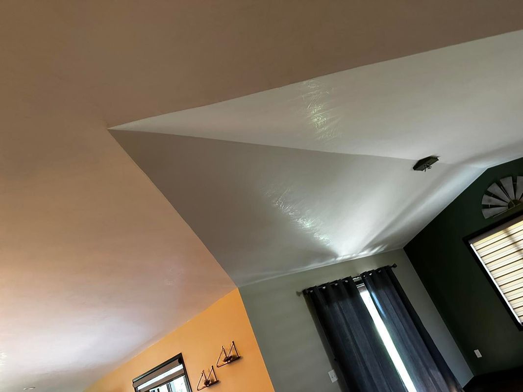 Angled white ceiling with black light fixture, dark curtains, and green wall.