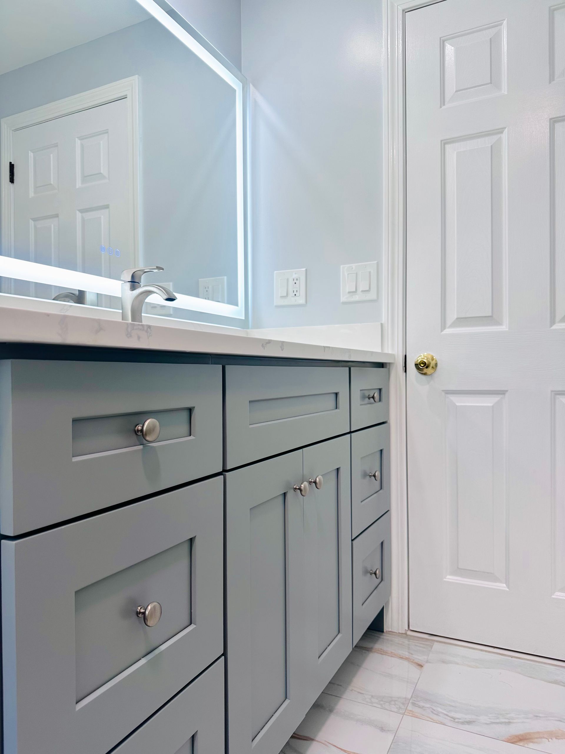 Bathroom vanity with gray cabinets, white countertop, sink, mirror, and a closed white door