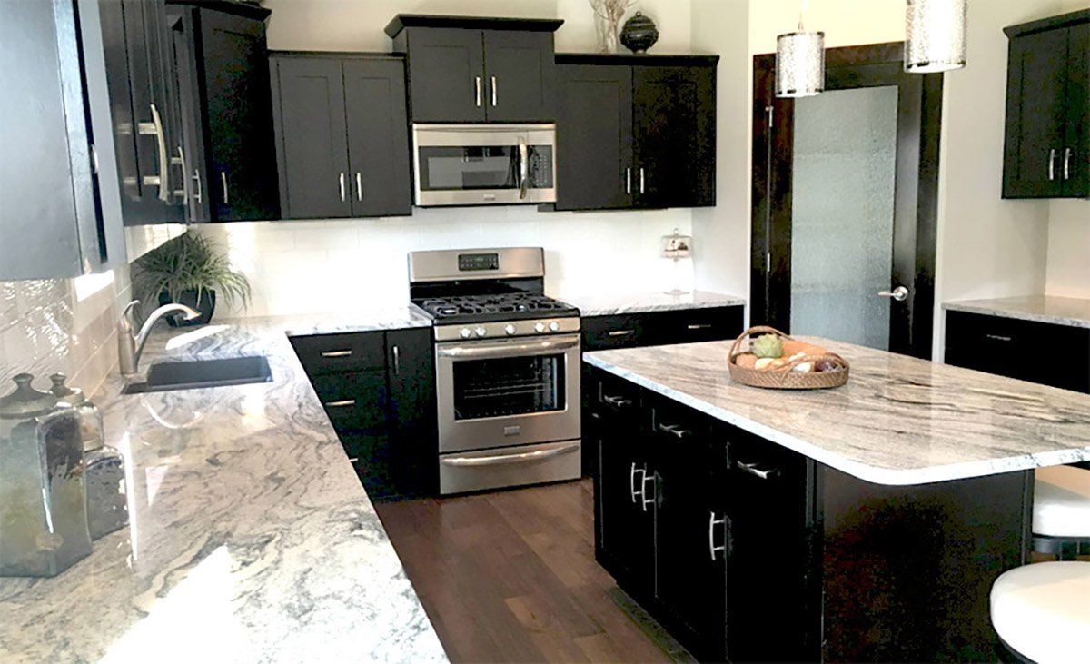 Modern kitchen with dark cabinets, stainless steel appliances, and a marble island counter