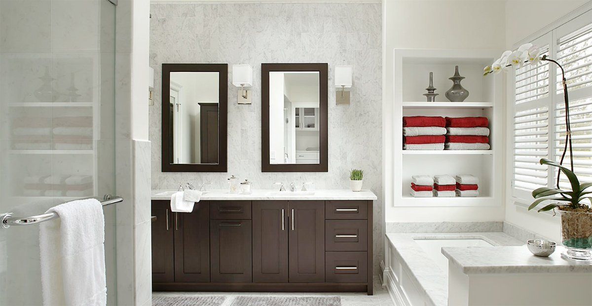 Modern bathroom with dark wood vanity, twin mirrors, white tile, and red towels in a wall niche