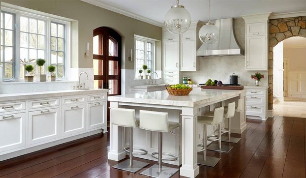 Bright white kitchen with island, dark wood floors, and large windows in a spacious open layout