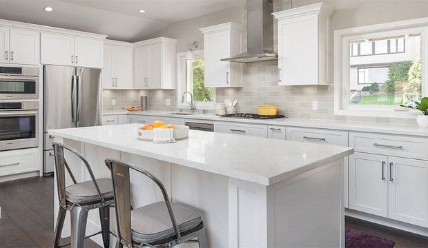 Bright modern white kitchen with island, stainless steel appliances, and bar stools