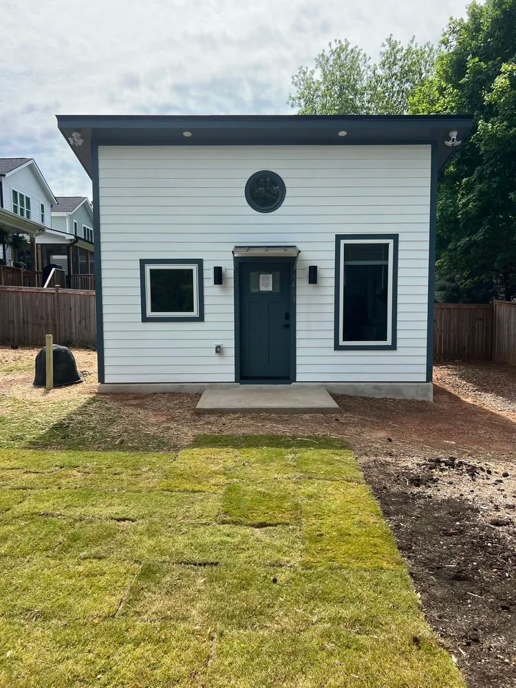 Small white modern house with black trim, a centered front door, and a lawn in front
