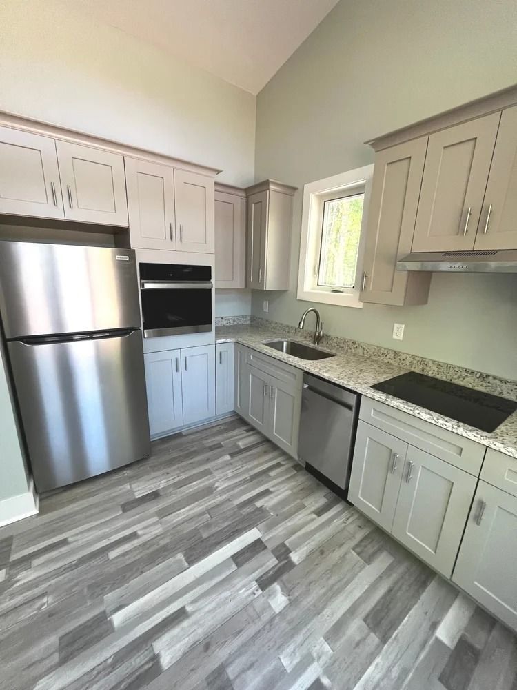 Modern kitchen with stainless steel appliances, beige cabinets, gray tile floor, and a window over the sink