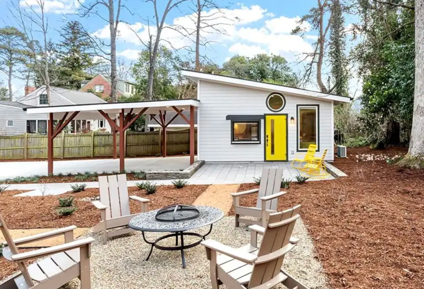 Backyard patio with fire pit seating and a small white shed with a bright yellow door