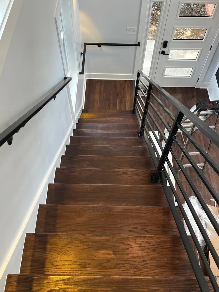 Stairwell with dark wood steps, black metal railing, and white walls overlooking a front entry door.
