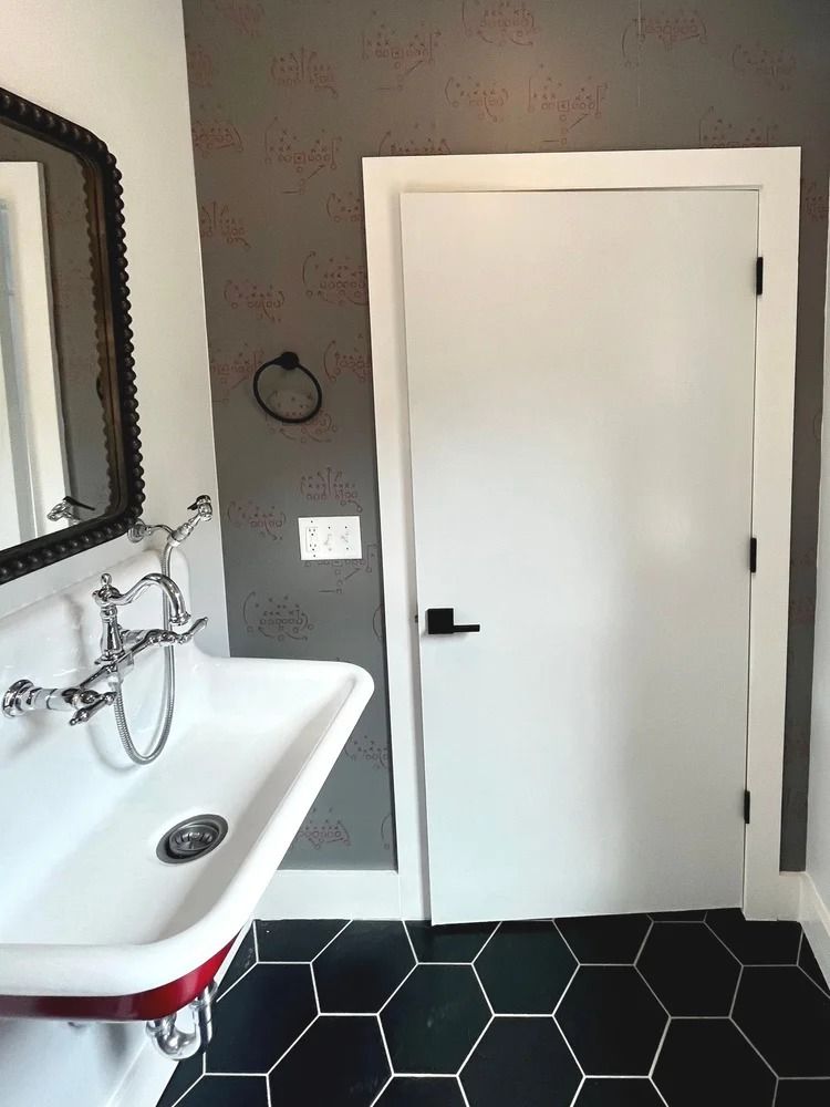Small bathroom with white sink, black hex tile floor, gray walls, and a closed white door.