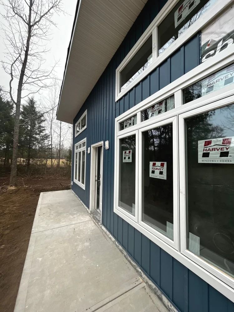 Blue commercial building with large windows and a concrete sidewalk along the side