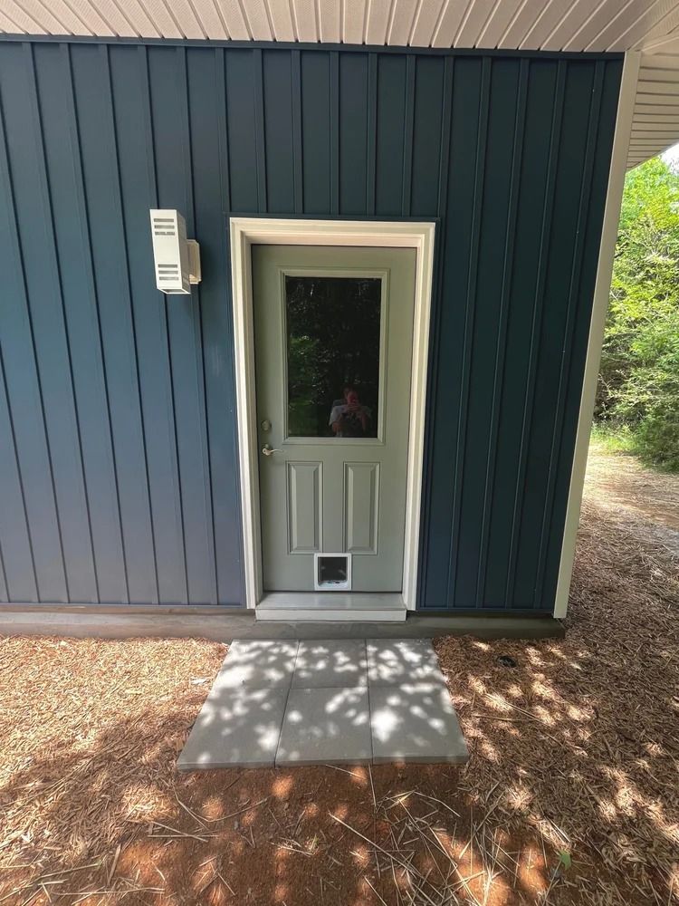 White exterior door with mail slot on a blue-sided building, beside a small concrete step.