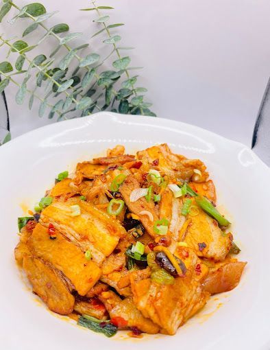 A white plate topped with a stew of meat and vegetables.
