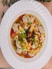 A white plate topped with a bowl of food on a table.